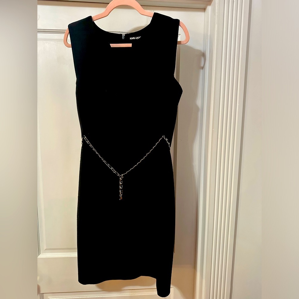 Black sleeveless dress with chain belt.